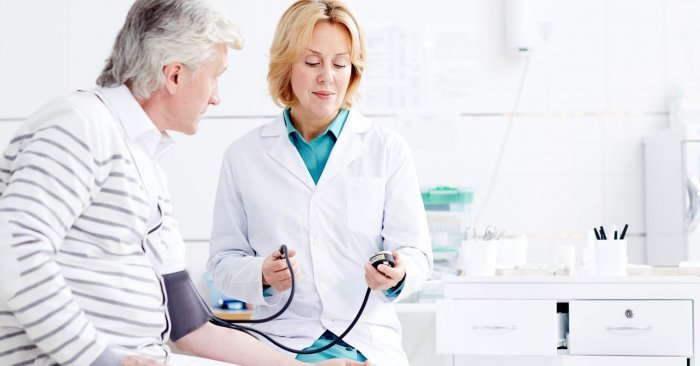 Therapeutist measuring blood pressure of mature patient during appointment